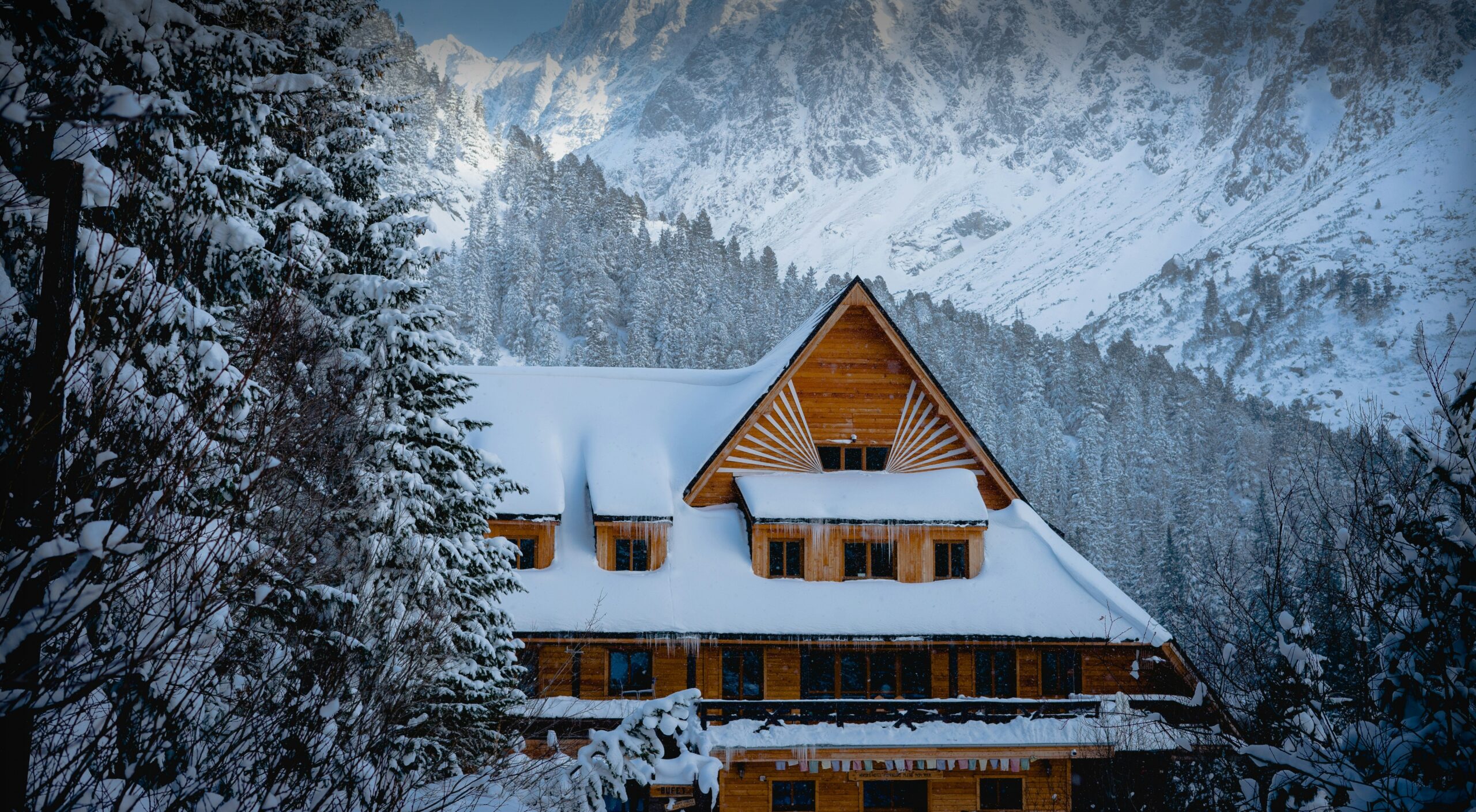 Large traditional wooden chalet under the snow in an alpine landscape