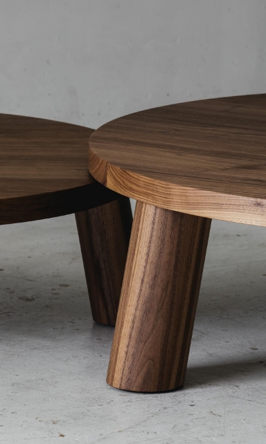 Détail de tables basses rondes et minimalistes en bois sombre texturé