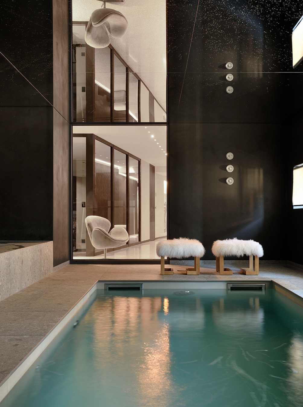 Luxurious indoor chalet swimming pool with fur armchairs and poufs