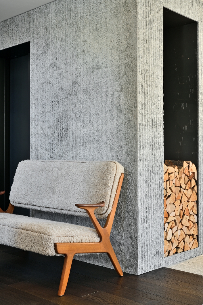 Small vintage Scandinavian sofa in curly sheepskin in front of a textured wall