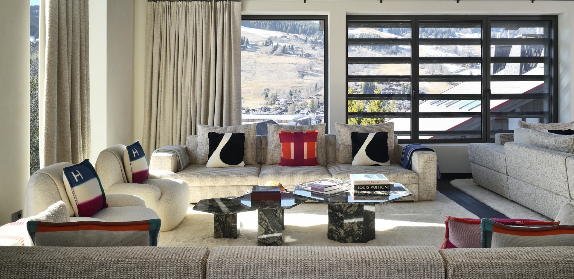 Contemporary luxury living room in a Courchevel chalet, interior design by Studio Norki featuring beige sofas and a view of the snow-covered slopes