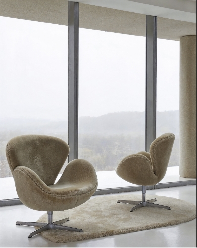Salon de chalet contemporain avec fauteuils Swan face à une immense baie vitrée ouvrant sur la forêt brumeuse
