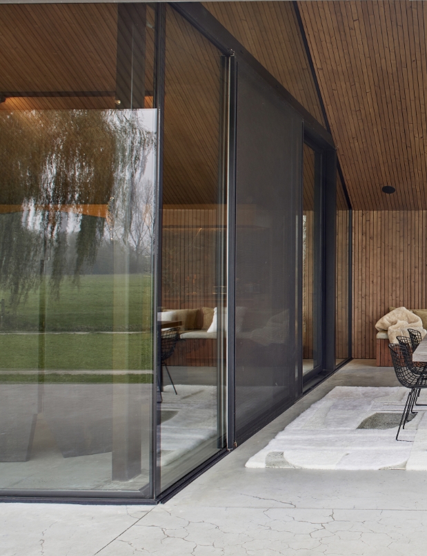Terrasse de chalet contemporain mêlant de grandes baies vitrées et structure métallique noire