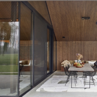 Terrasse moderne de chalet de luxe avec table dressée sous un avant-toit en bois