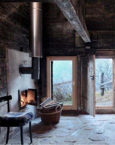 Intérieur de chalet rustique et intimiste avec poêle à bois en métal et foyer allumé