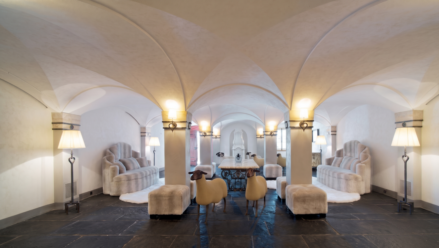 Vaulted lounge space in the St. Moritz chalet with bespoke sofas, ottomans, and rugs by Norki